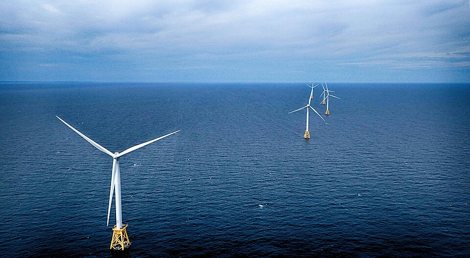 Offshore wind farm at dusk with turbines silhouetted against sunset